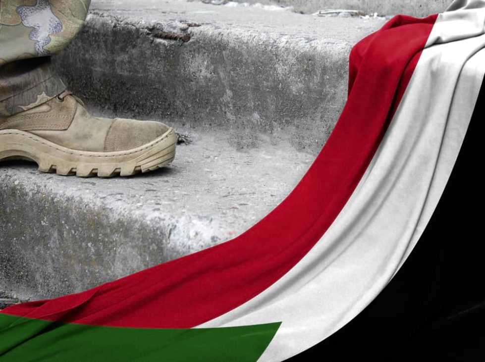 Военный рядом с флагом Судана фото
